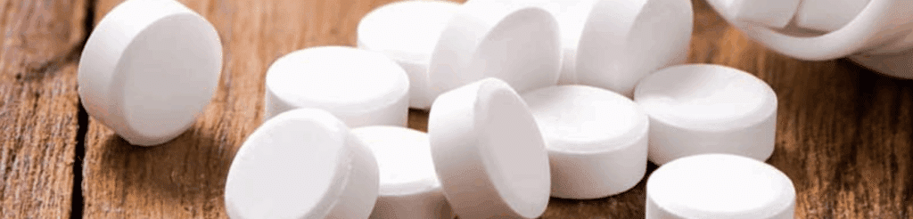 White Klonopin tablets spilled onto a wooden surface, representing a commonly prescribed benzodiazepine used for anxiety and seizures.